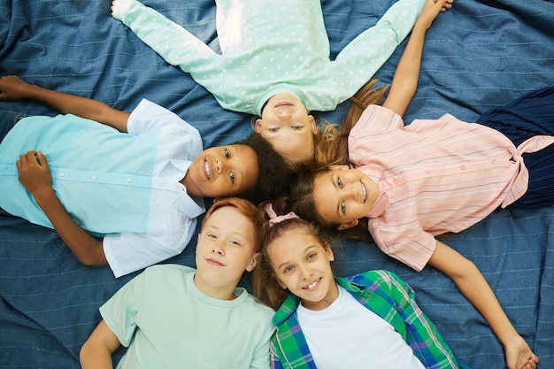 Foto vista dall'alto di un gruppo multietnico di bambini che giace in cerchio su una coperta all'aperto