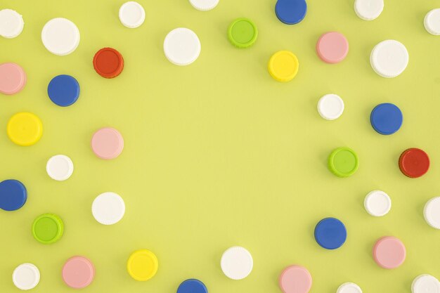 Photo top view of multicolored plastic bottle caps in a chaotic pattern on a green background