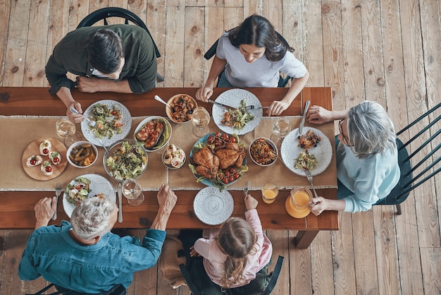 Top view of multigeneration family communicating and smiling while having dinner together