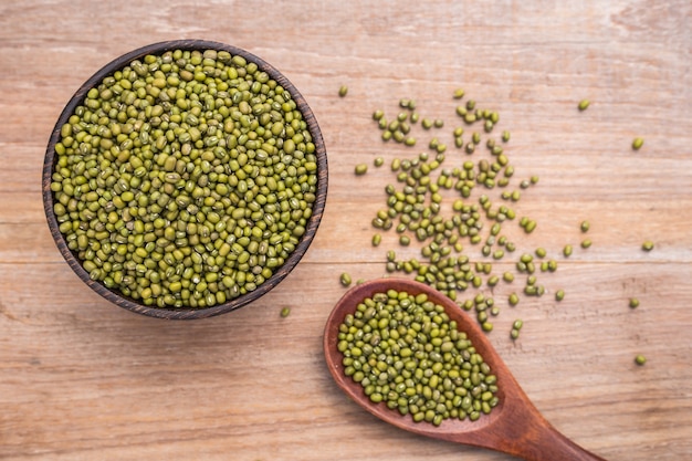 Top view mung beans in wooden bowl put on wooden plank background