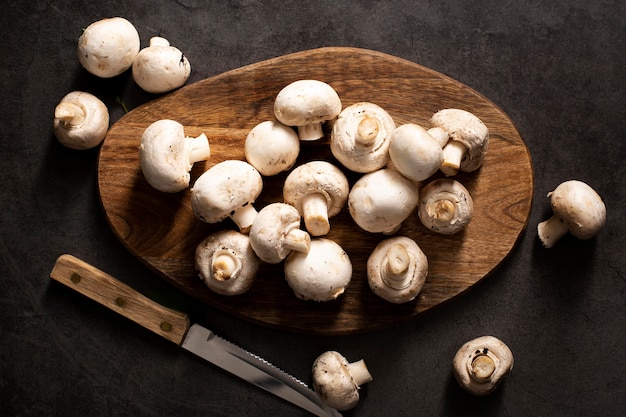 Photo top view mushrooms on cutting board with knife