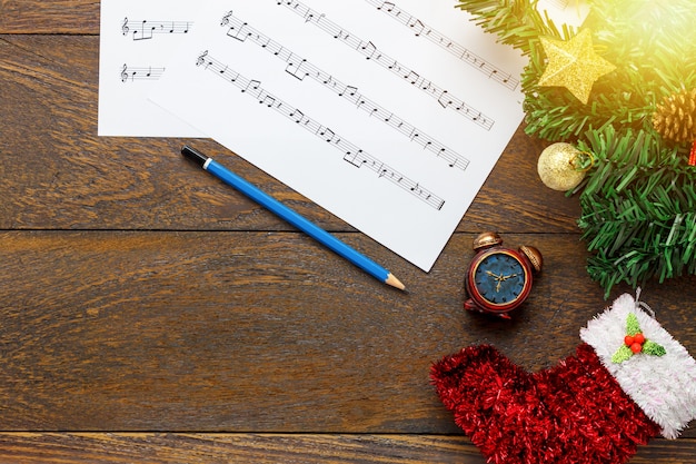 Top view music sheet note paper and christmas decoration on wood background