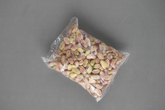 Top view of natural pistachios in a packet on grey background