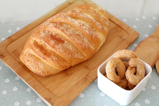 Вид сверху на естественно ферментированный хлеб на деревянной доске и сахарные пончики, селективный фокус