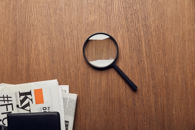 Top view of newspaper near magnifier on wooden surface