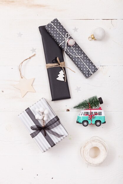 Вид сверху на красивые рождественские подарки, упакованные в черную и полосатую бумагу, и игрушечный ретро-минивэн