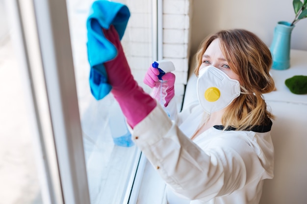  Top view of a nice working young woman while cleaning windows in the house