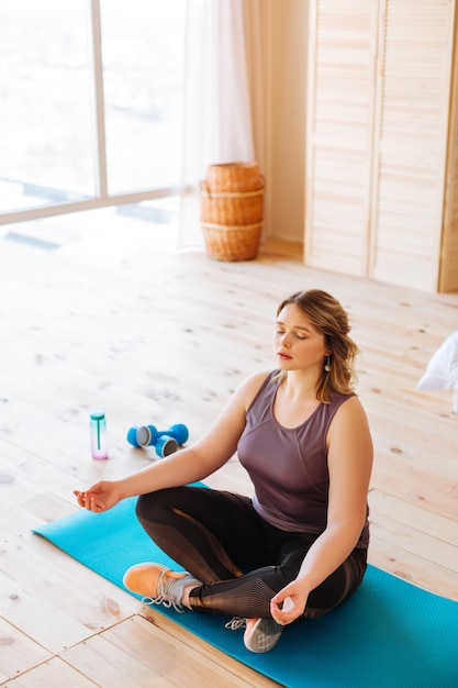  Top view of a nice young woman sitting with her eyes closed while practicing yoga