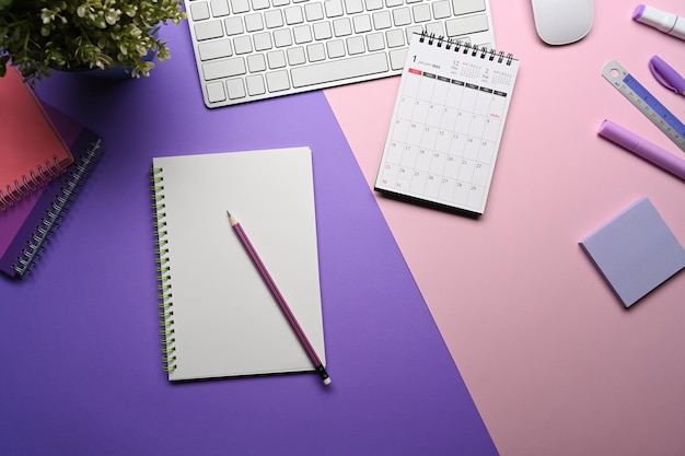 Top view notebook, calendar and stationery on purple
background.