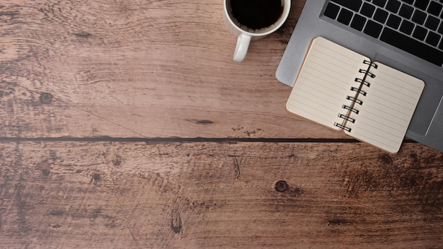 Tazza di caffè del taccuino di vista superiore e computer portatile su fondo di legno