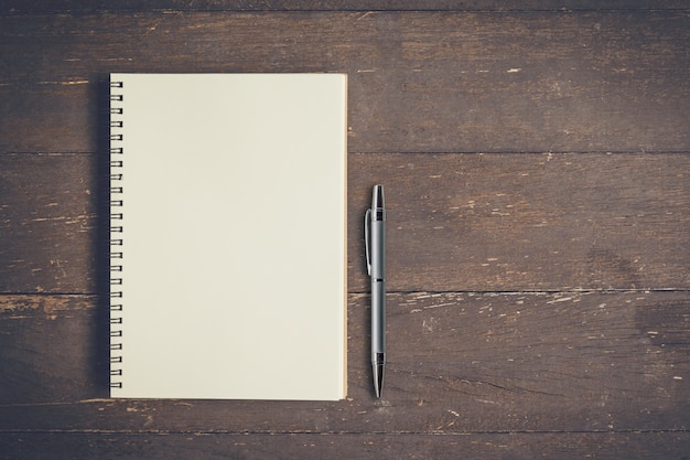 Top view notebook and pen on wood table with space, Vintage filter.