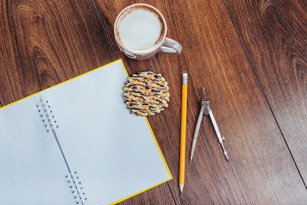 Top view of notebook, stationery, drawing tools and a few cups coffee.