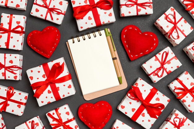 Top view of notebook, white gift boxes and red textile hearts