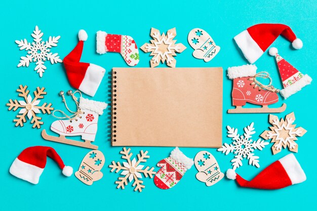 Top view of notebook with Christmas decorations and Santa hats on blue.