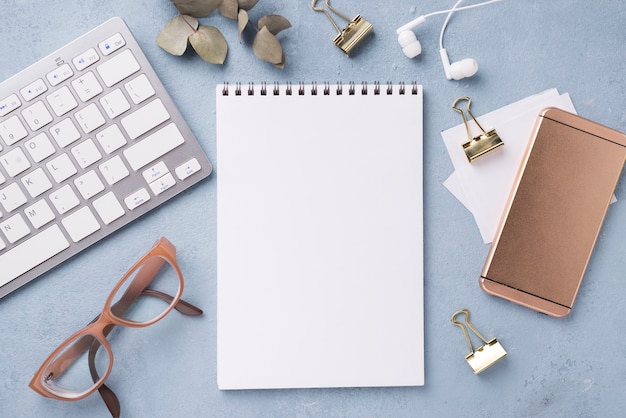 Photo top view of notebook with glasses and smartphone on desk