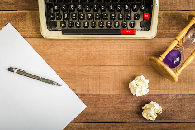 Top view of notebook on the wood table, typewriter, old telephone and earphone