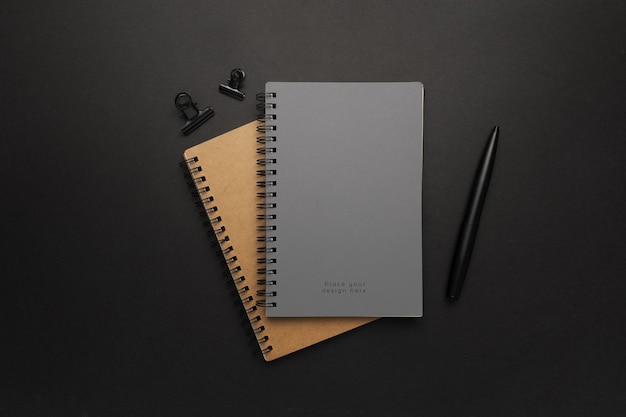 Top view of notebooks and a pen on a black surface