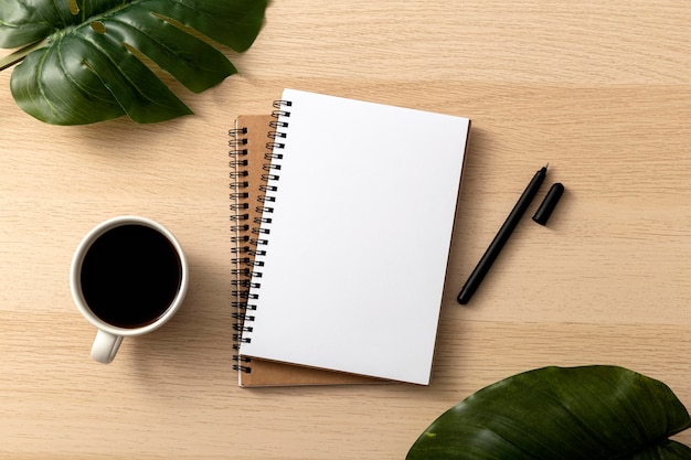 Photo top view of notebooks with leaves and coffee mug