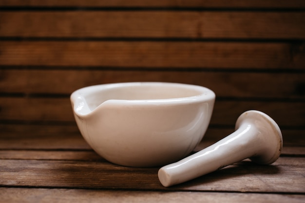 Top view of oat grains in the porcelain mortar bowl on the old wooden table