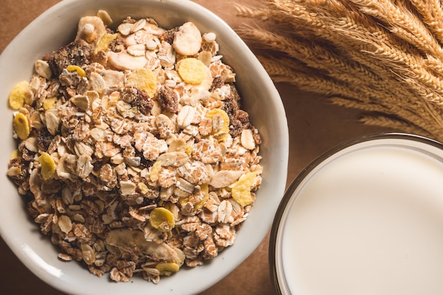 La vista superiore della farina d'avena si sfalda in una ciotola e latte sulla tavola di legno.