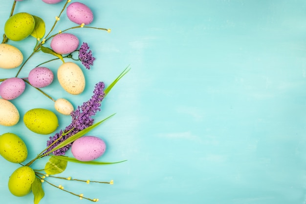 Фото Вид сверху красочные пасхальные яйца и весенние цветы на бирюзовом фоне с пространством сообщений