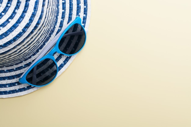 사진 베이지 색 표면에 모자와 파란색 선글라스의 상위 뷰