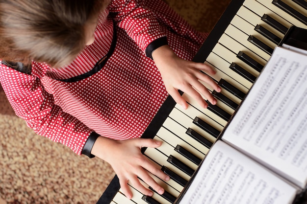 Вид сверху молодой девушки, играющей на пианино дома