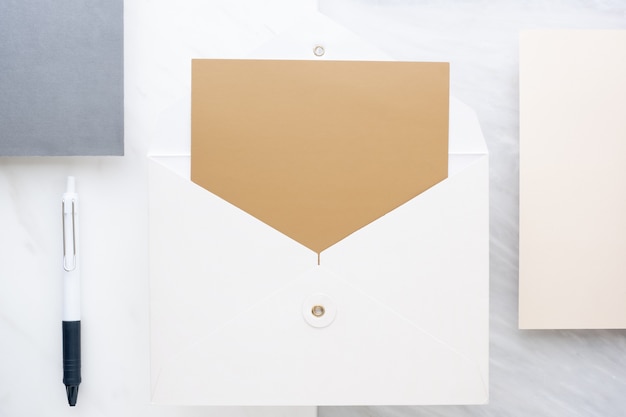 Фото Вид сверху пустой золотой карты в белом конверте на столе