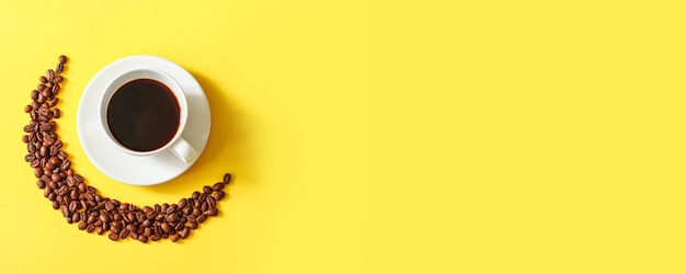 写真 最小限の黄色の水平方向の背景にコーヒーとコーヒー豆のカップの上面図