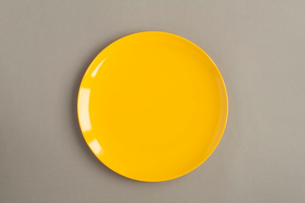 Фото Вид сверху пустой желтой тарелки на сером фоне