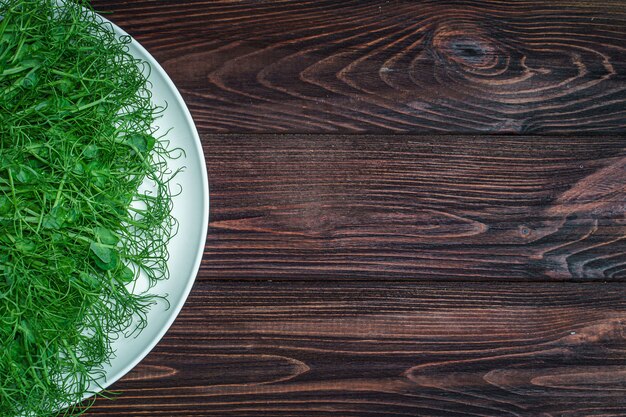 Фото Взгляд сверху ростков свежесрезанного гороха microgreen на плите на деревянной поверхности