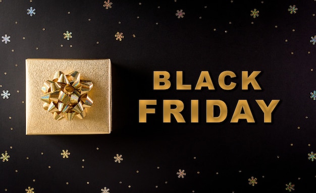 Фото Вид сверху золотых рождественских подарочных коробок на черном фоне с текстом черной пятницы