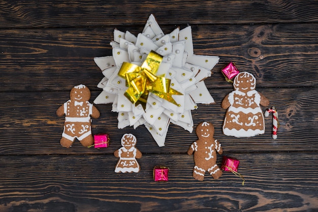 사진 나무 책상에 작은 선물이 있는 귀여운 진저브레드 가족이 있는 홈메이드 진저브레드 크리스마스 트리의 최고 전망. 계절 제안 및 휴일 엽서 모형
