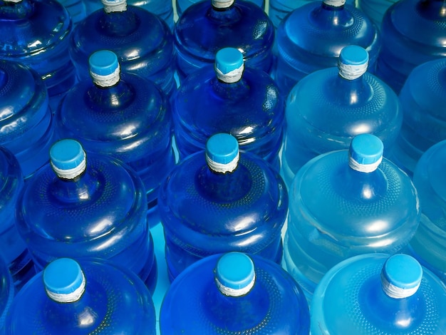 사진 플라스틱 큰 병 들 을 줄지어 놓은 상단 으로부터 볼 때, 그 안 에는 청정 된 음료 물 의 파란색 갤런 이 있다