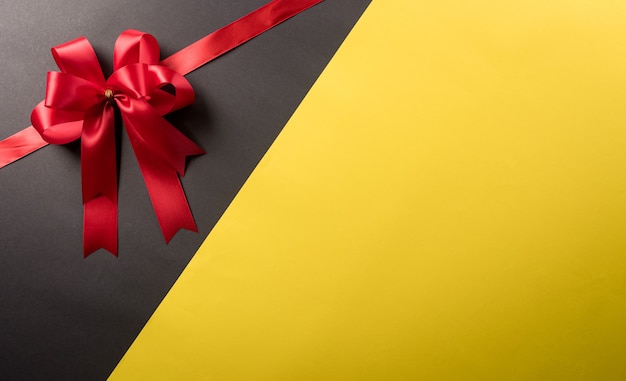 Фото Вид сверху украшения красной лентой на черном и желтом фоне. день бокса концепции покупок и состав черной пятницы.