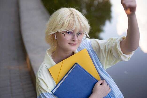 Фото Вид сверху на подростковую девушку, делающую селфи. студент с желтыми и синими папками.
