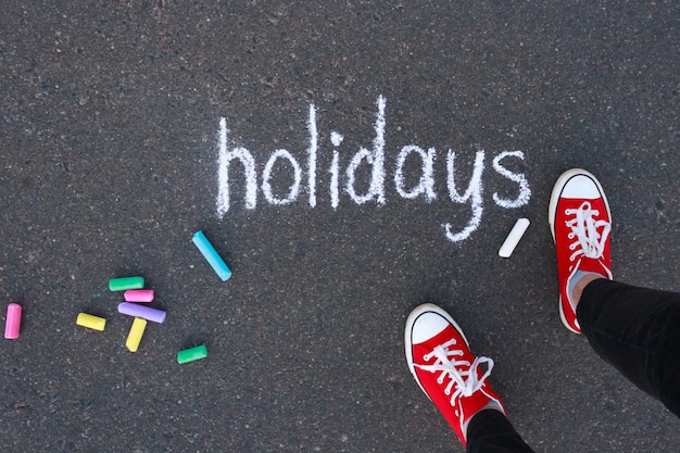 写真 歩道の色のチョークと足に白いチョークで書かれた休日という単語の平面図