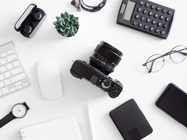 top view of office desk table with calculator, notebook, plastic plant, smartphone and keyboard on white