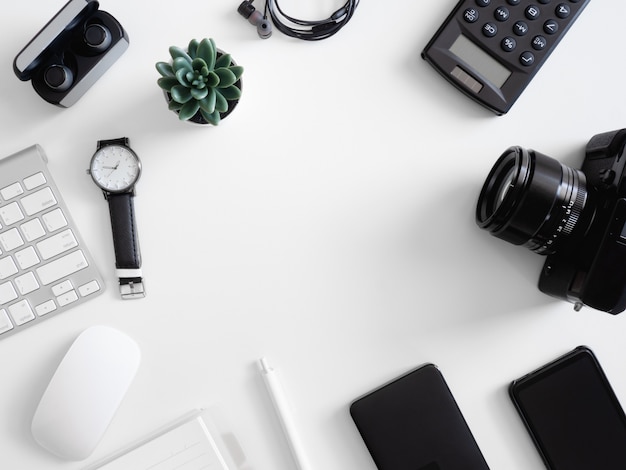 top view of office desk table with  calculator, notebook, plastic plant, smartphone and keyboard on white