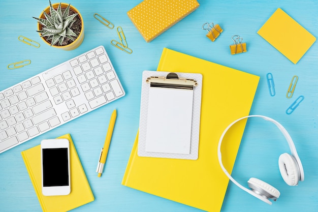 Top view of office desk. Table with keyboard, smartphone, clipboard and office supplies. Flat lay home office workspace, remote work, distant learning, video conference, calls idea