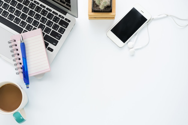 Vista dall'alto dell'area di lavoro della scrivania con tazza di caffè, taccuino, smartphone e tastiera