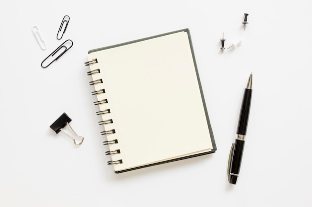 Top view of office stationery with notebook and paper pins