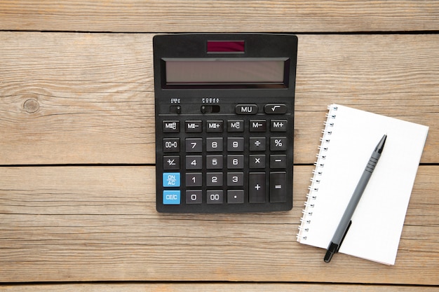 Top view office table calculator with pen and notebook on the table for business with copy space.