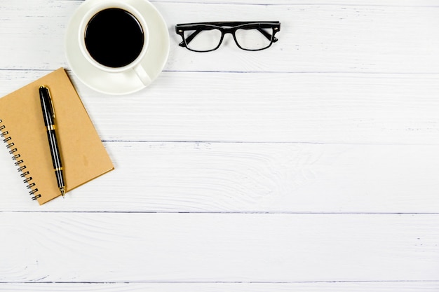 Vista superiore dell'ufficio, scrittorio bianco di legno con caffè, vetri, penna, concetto di affari.