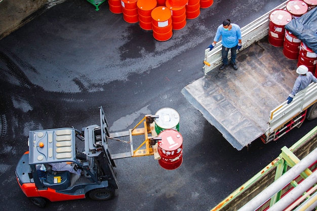 Top view oil barrels forklift truck move for on the transportation truck male worker help arrange.