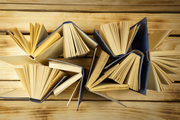Foto vista dall'alto di vecchi libri con copertina rigida sulla superficie del legno. superficie dai libri. libri aperti, pagine sfogliate.