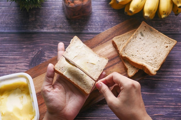 Top view of omen hand spreading butter on a bread