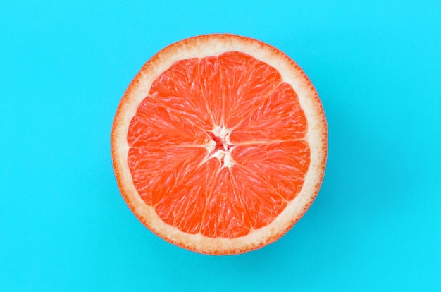 Top view of an one grapefruit slice on bright background in blue color. 