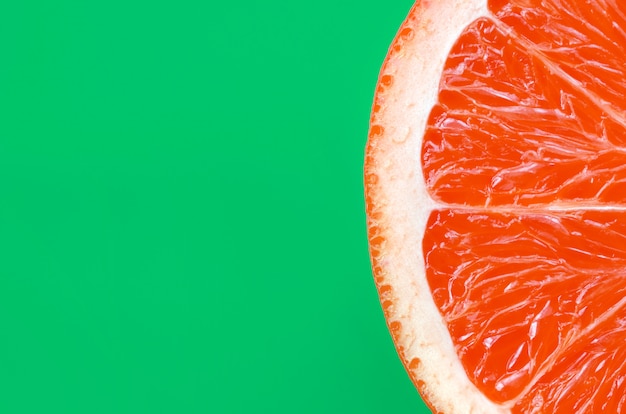 Photo top view of an one grapefruit slice on bright background in green color