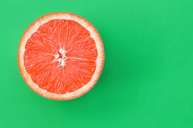 Top view of an one grapefruit slice on bright green